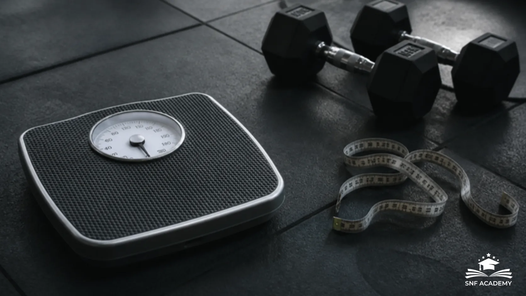 Personenwaage, Massband und Kurzhanteln auf dem Boden eines Fitnessstudios