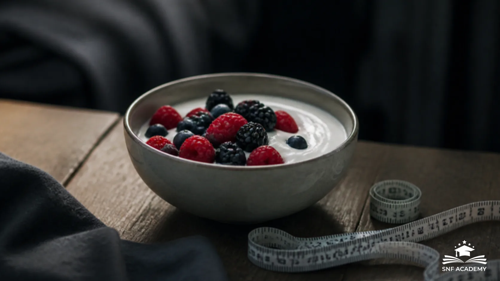 Schale Naturjoghurt mit Beeren auf einem Holztisch neben einem Massband